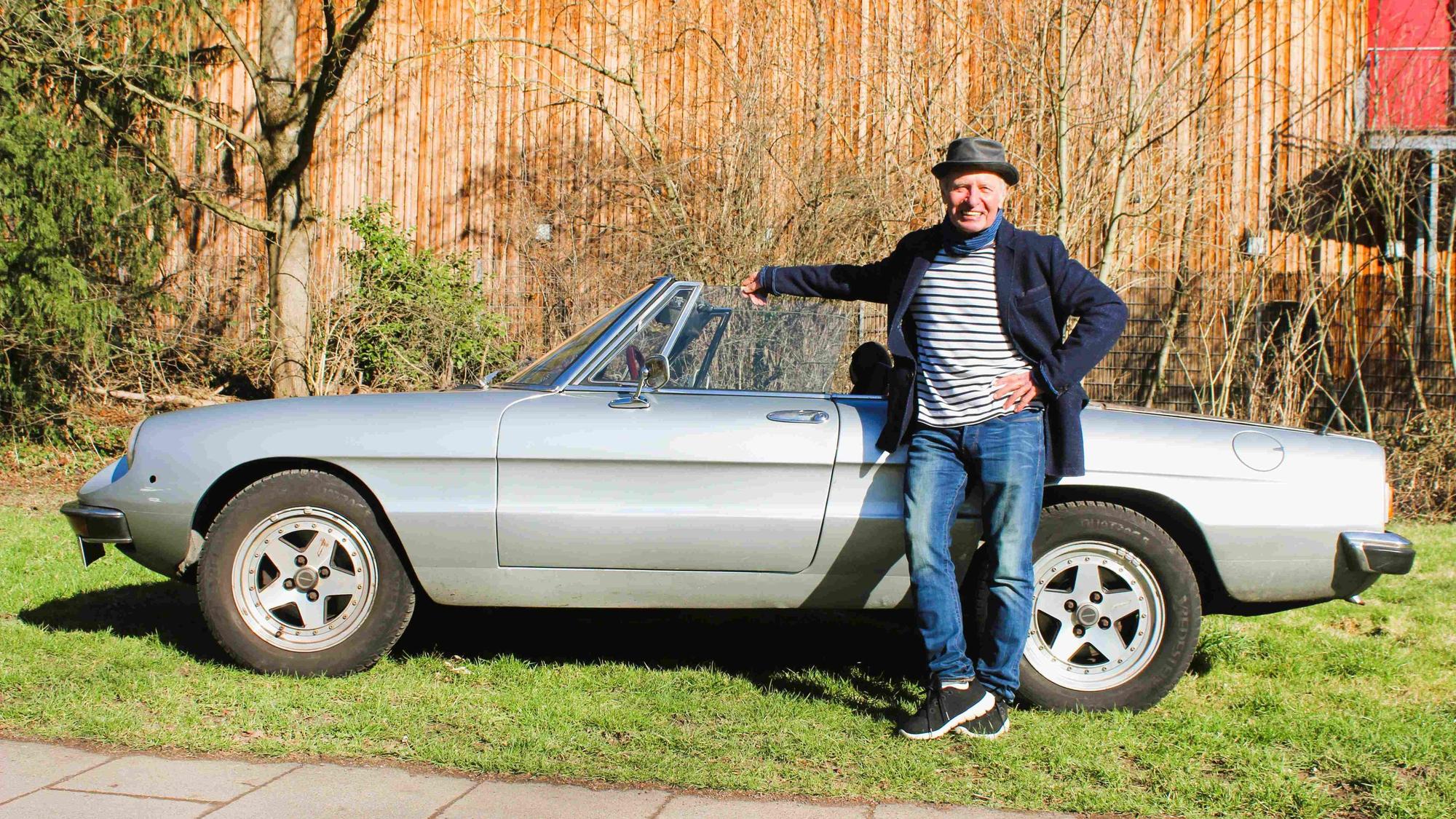 Das Bild zeigt Didi Jünemann vor seinem Alfa Romeo Spider.
