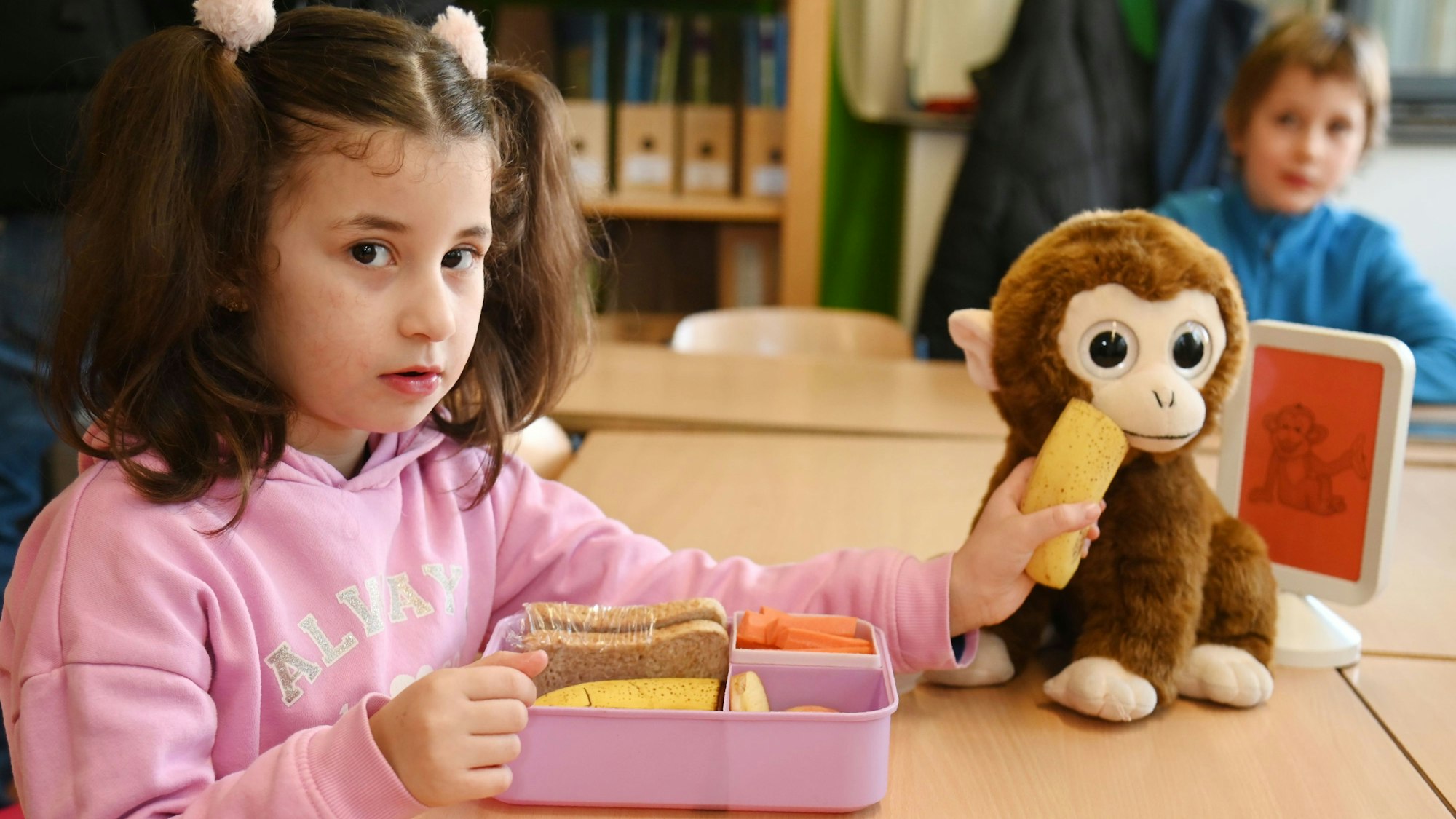 Eine Schülerin füttert das Maskottchen der Affenklasse Alma mit Obst. Bananen liefert Feldling freilich nicht, sondern nur Produkte aus dem Rheinland.