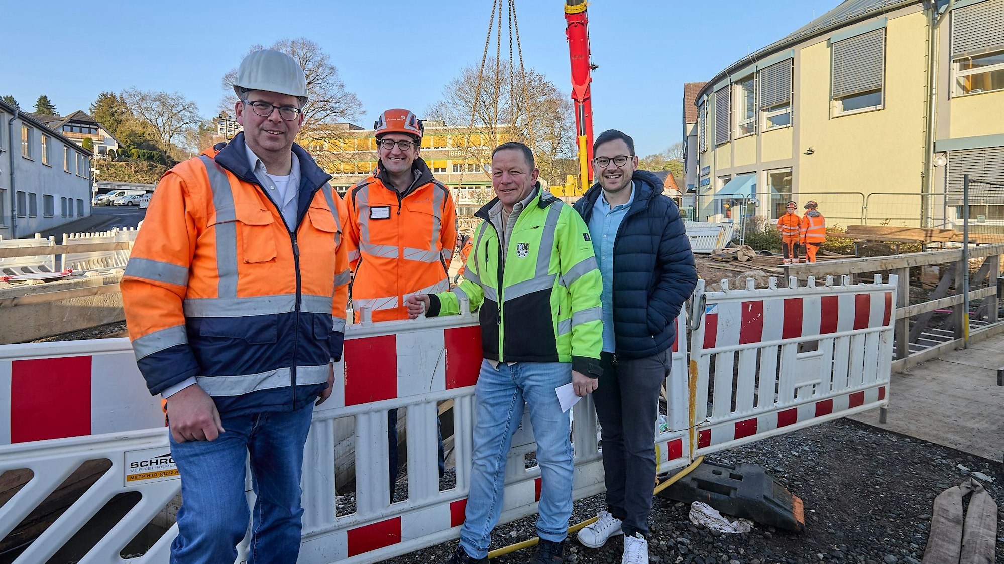 Vier Männer stehen an den Absperrbaken der Baustelle in Kall.