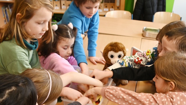Die Schüler und Schülerinnen der Affenklasse greifen beim Obst zu.