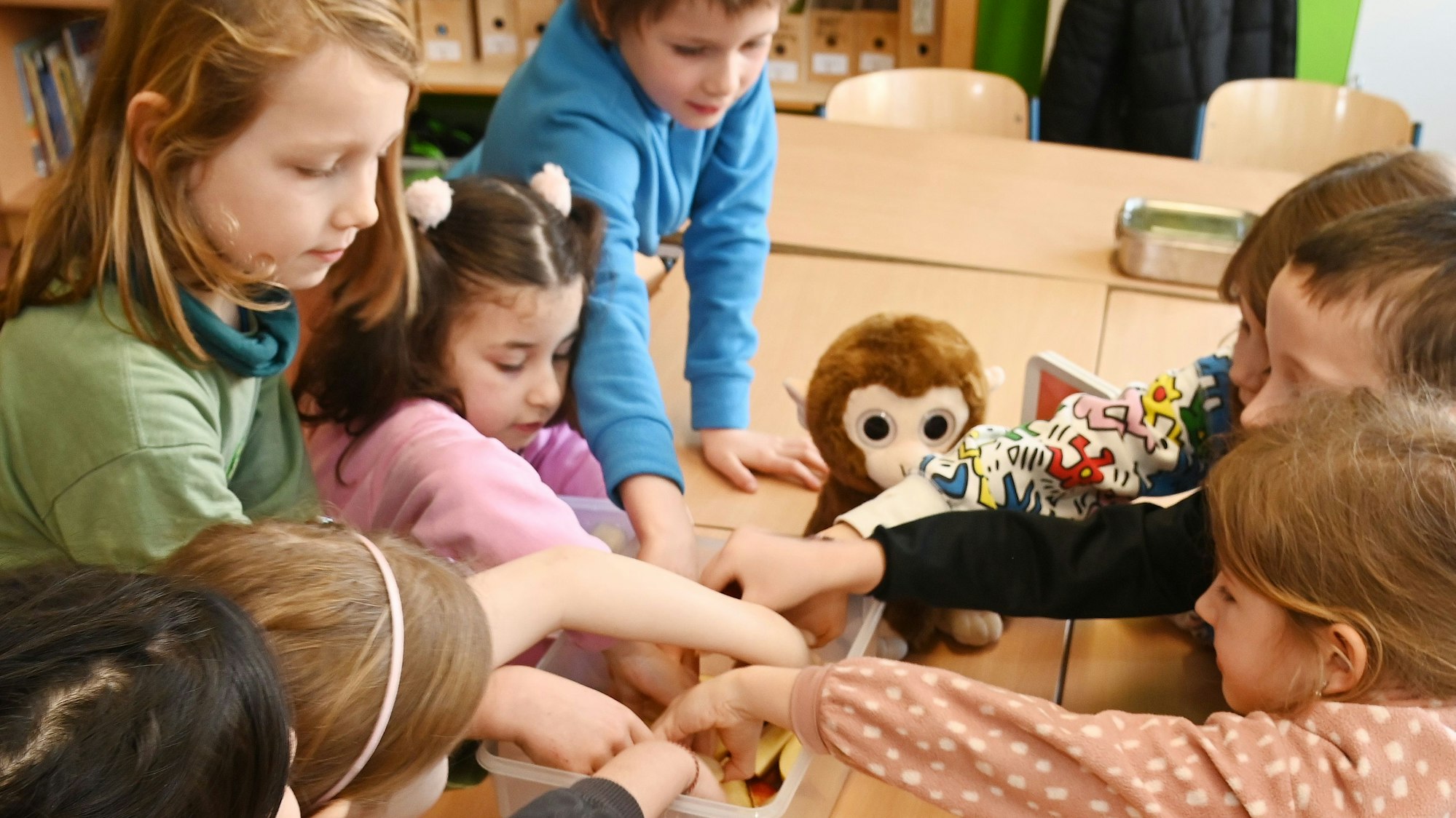 Die Schüler und Schülerinnen der Affenklasse greifen beim Obst zu.