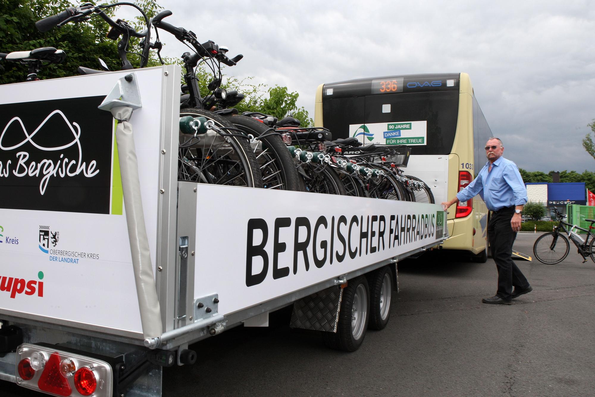 Ein Linienbus mit Fahrradanhänger, der Fahrer schließt die Seitenklappe.