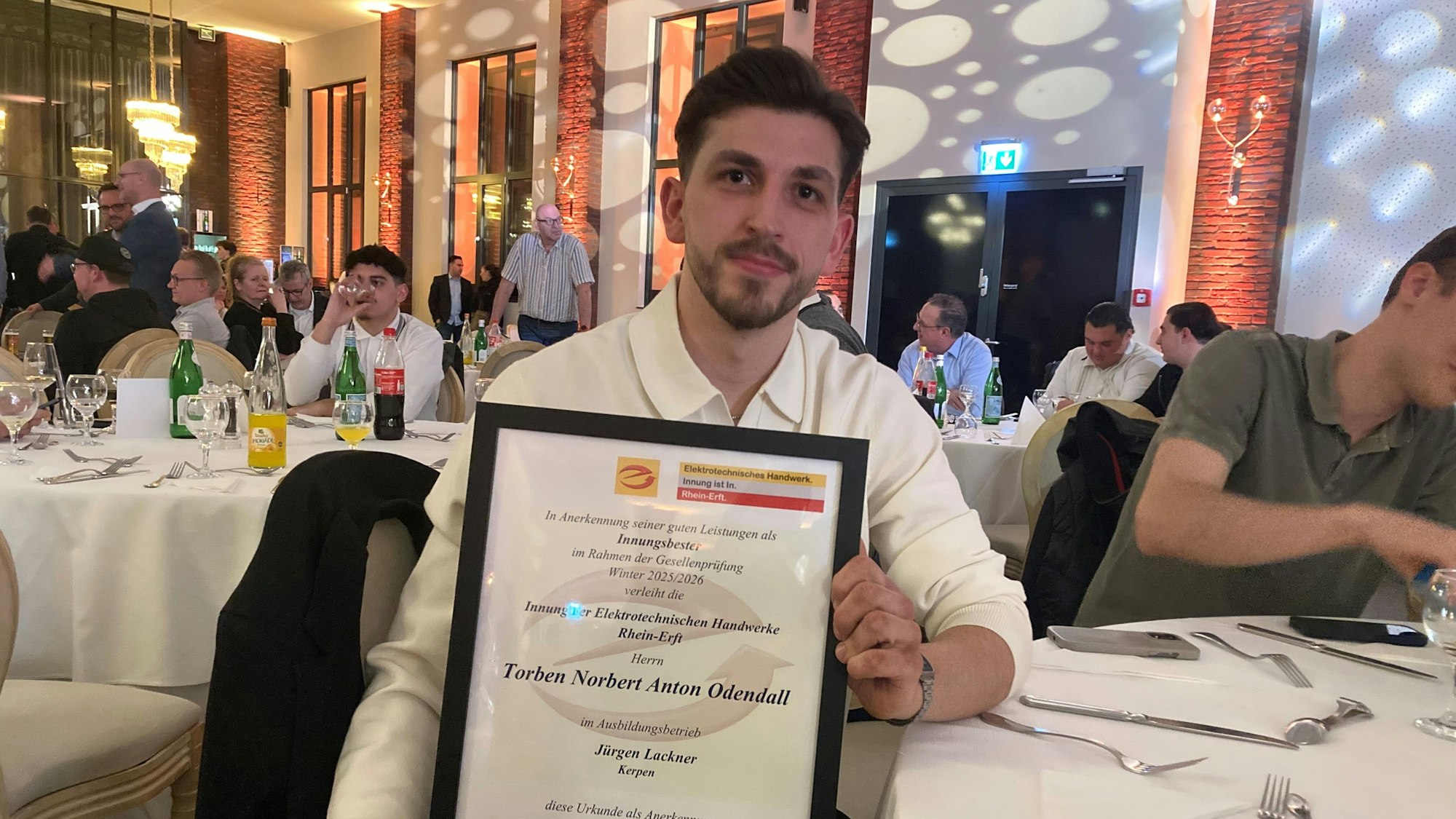 Das Foto zeigt einen jungen Mann, der eine Zeugnis-Urkunde hält.