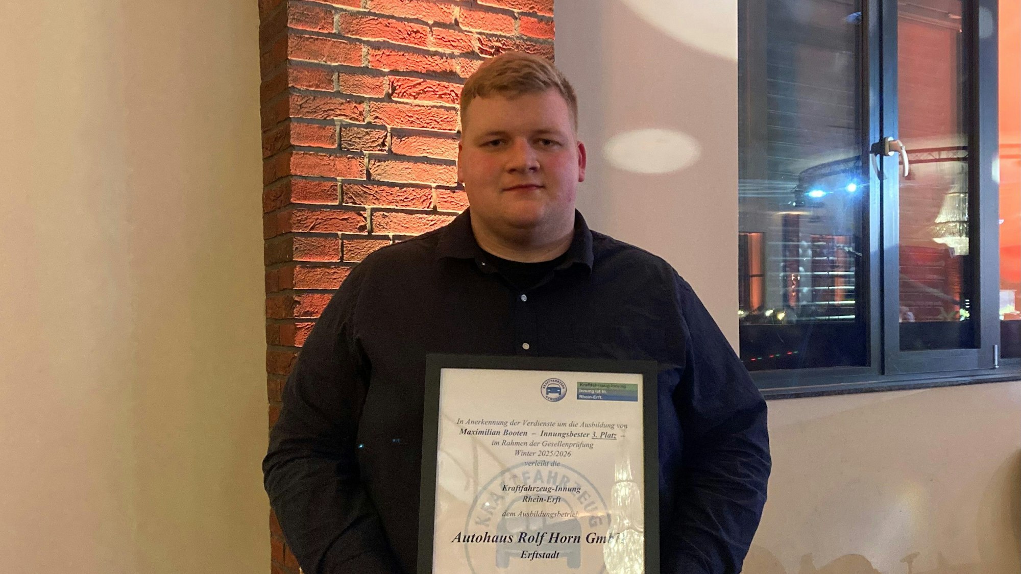 Das Foto zeigt einen jungen Mann mit einem Zeugnis in den Händen.