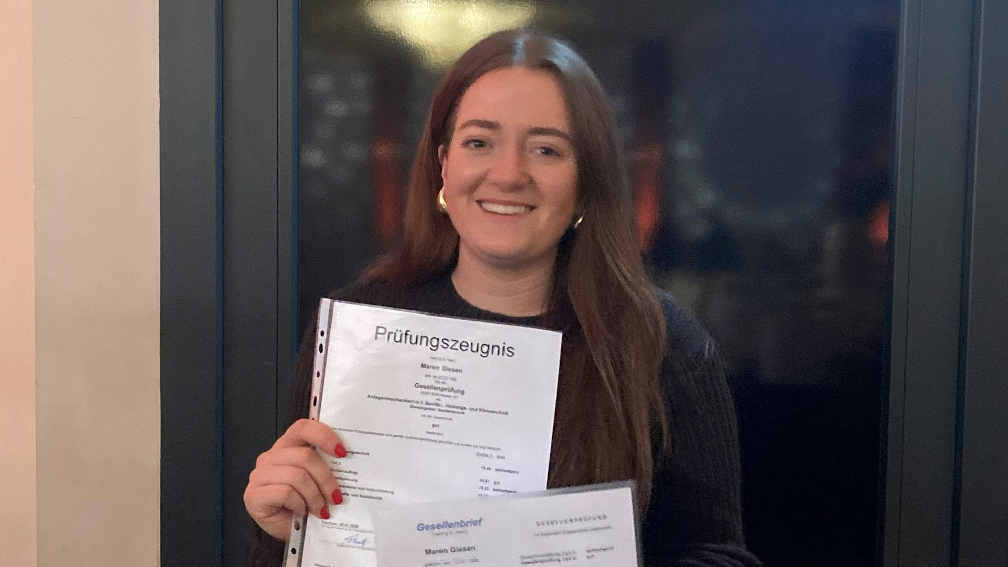 das Foto zeigt eine junge Frau, die ein Zeugnis in der Hand hält.