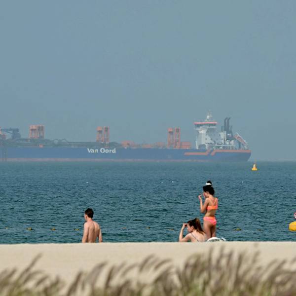 Menschen entspannen sich am Strand, während vor der Küste Dubais am 2. März Frachtschiffe vor Anker liegen. Der Krieg mit dem Iran hat Auswirkungen auf den Tourismus.