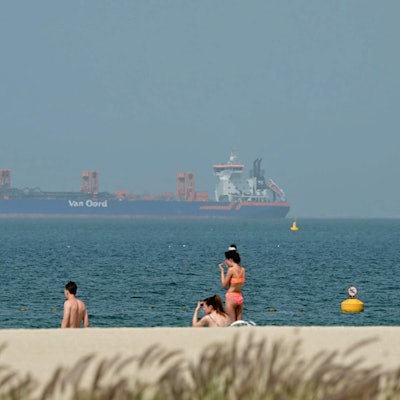 Menschen entspannen sich am Strand, während vor der Küste Dubais am 2. März Frachtschiffe vor Anker liegen. Der Krieg mit dem Iran hat Auswirkungen auf den Tourismus.
