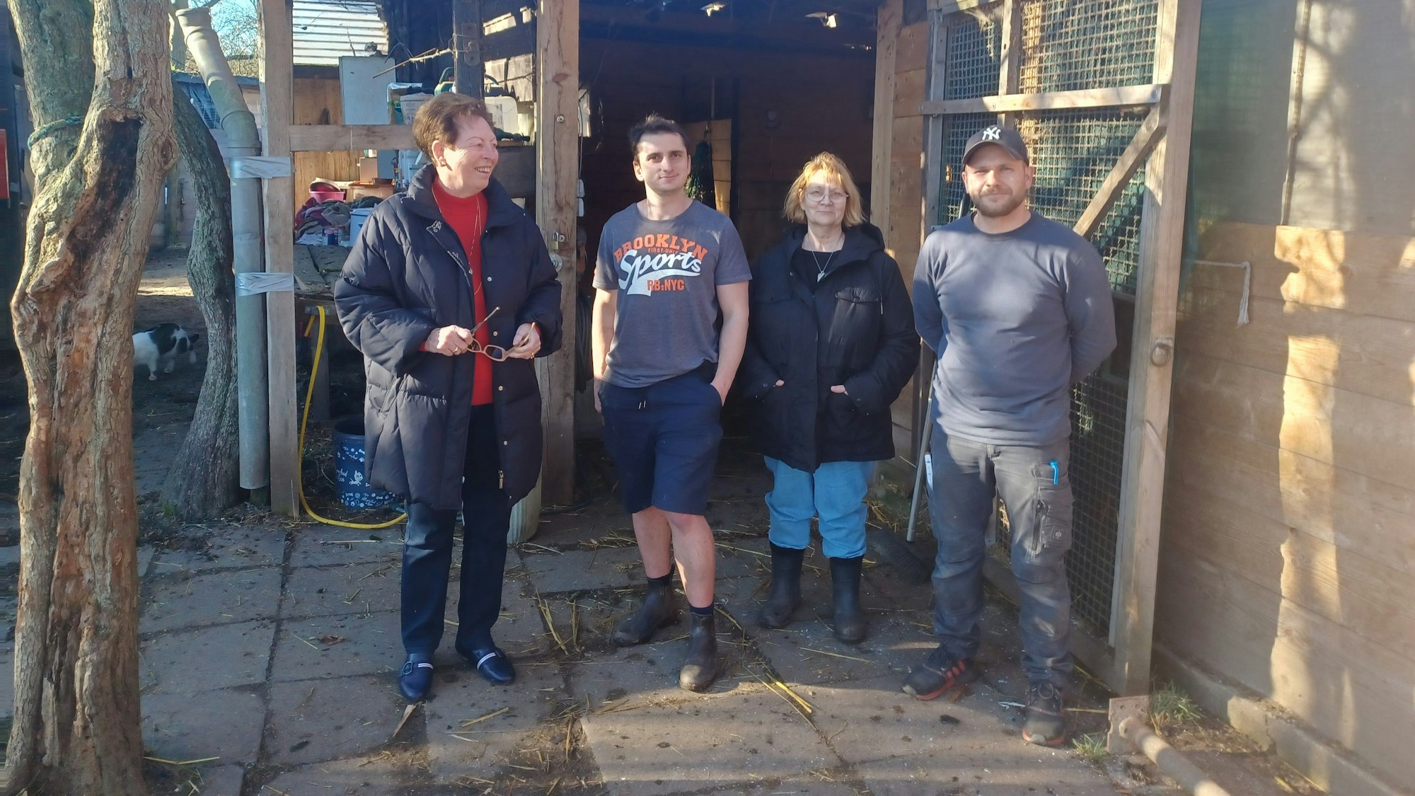 Vier Menschen stehen vor einem Stall.