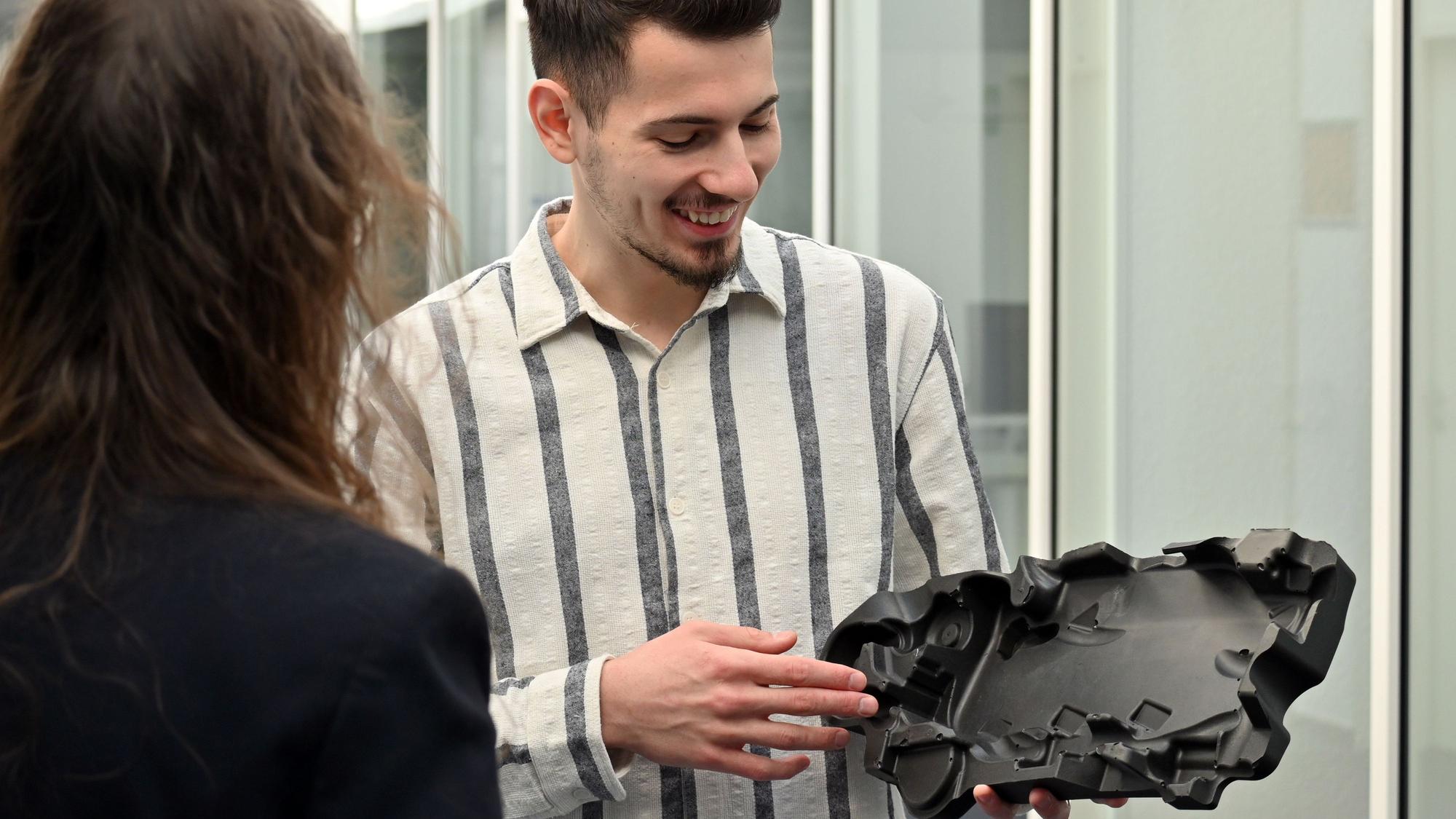Ein Mann hält ein Kunststoffbauteil in der Hand