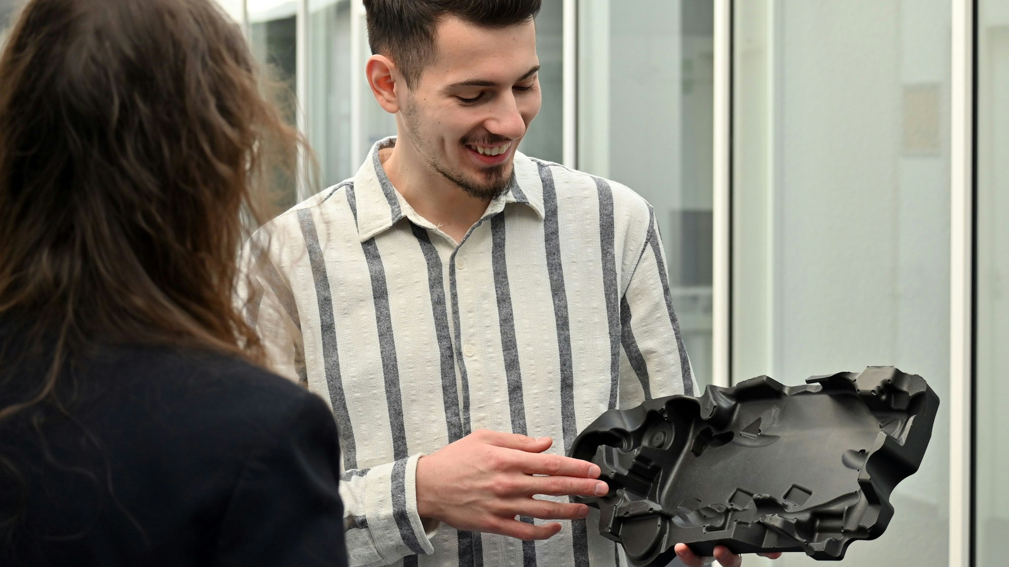 Ein Mann hält ein Kunststoffbauteil in der Hand
