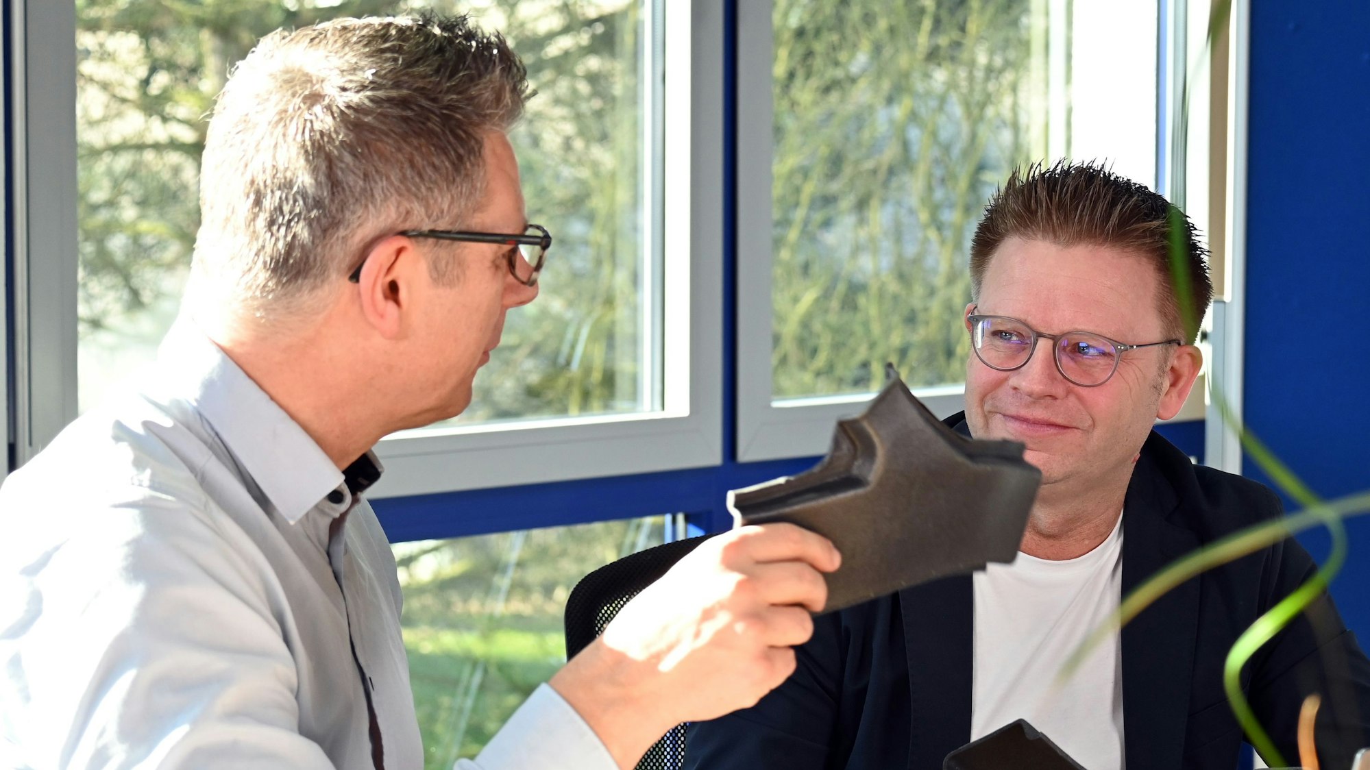 Zwei Männer – einer hat ein Kunststoffteil in der Hand