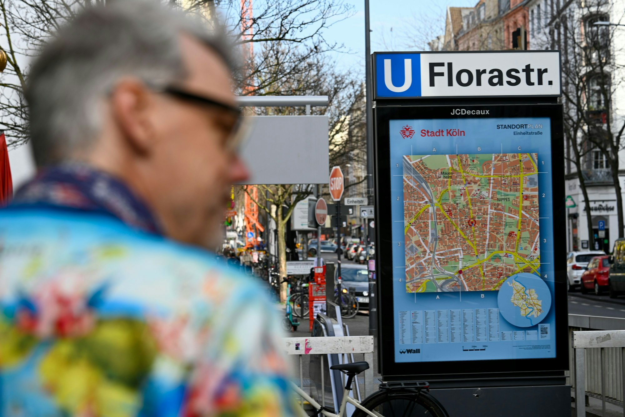 Ein Mann läuft eine Straße entlang. Ein U-Bahn-Schild weist auf die Station Florastraße hin.
