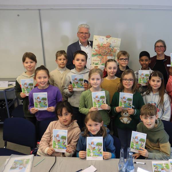 Die Kinder und der Beigeordnete, die sich zu einem Gruppenbild aufgestellt haben, präsentieren den Stadtplan.