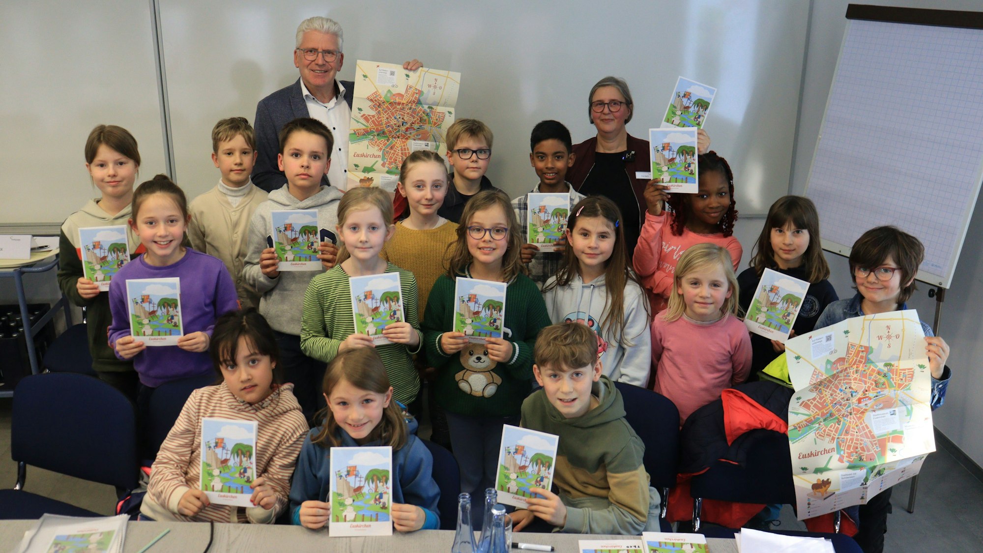 Die Kinder und der Beigeordnete, die sich zu einem Gruppenbild aufgestellt haben, präsentieren den Stadtplan.