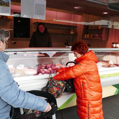Zwei Frauen stehen vor einem Marktstand in ihren Wintermänteln.