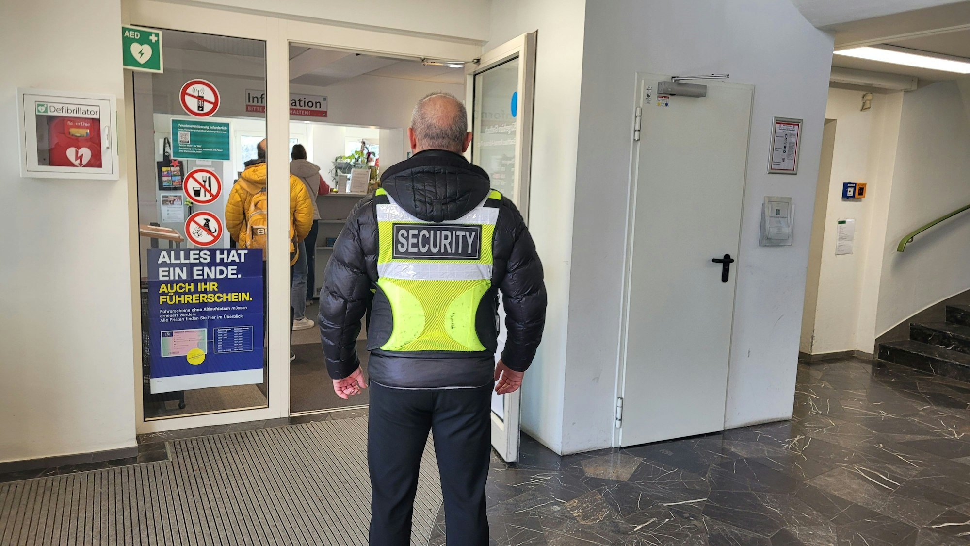 Der Sicherheitsmitarbeiter steht vor einer offenen Tür.