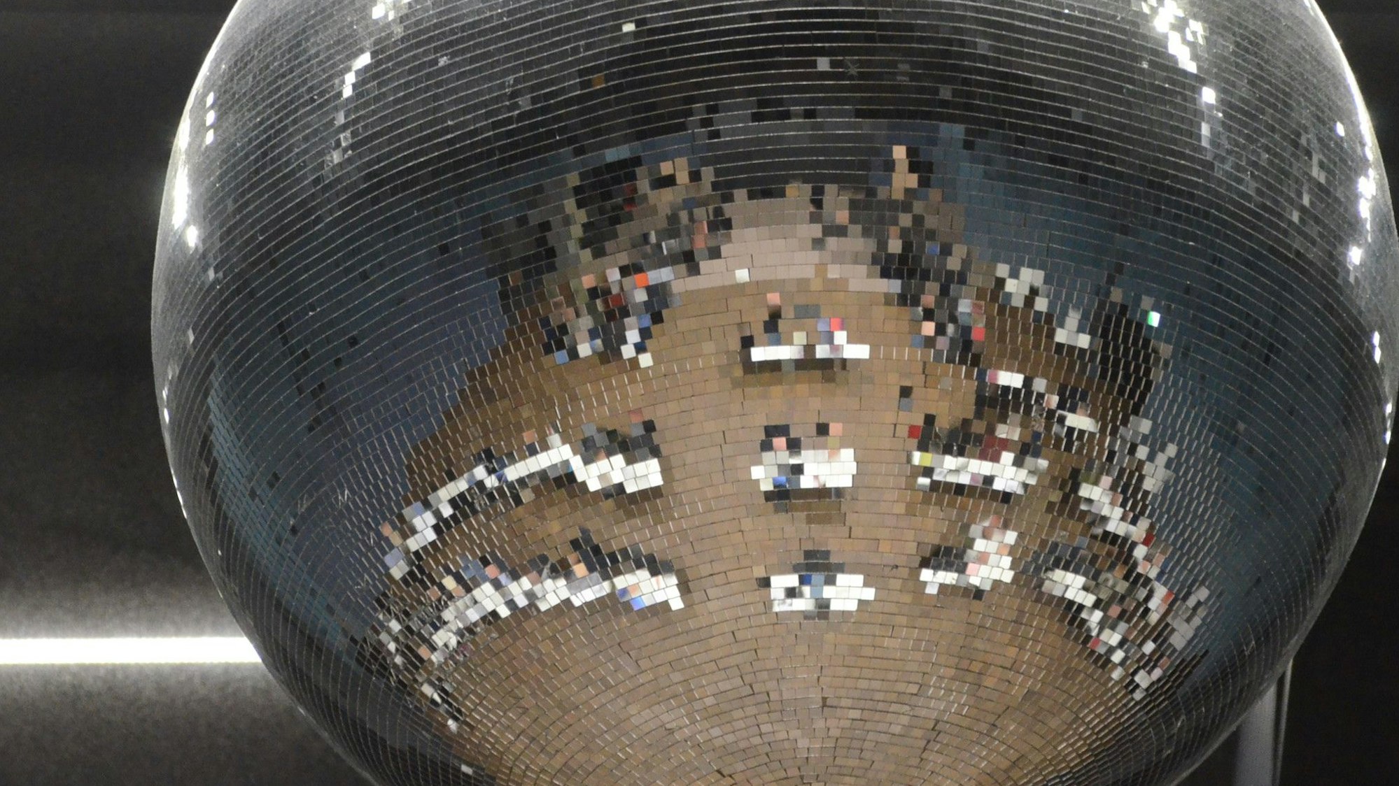 Tische und Stühle einer Gremiensitzung spiegeln sich in einer Discokugel.