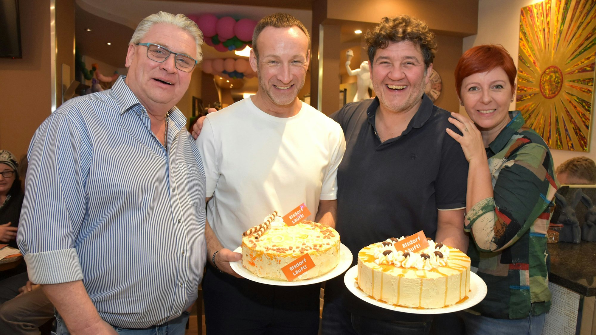 Drei Männer und eine Frau strahlen um die Wette, zwei Männer halten Torten in den Händen.