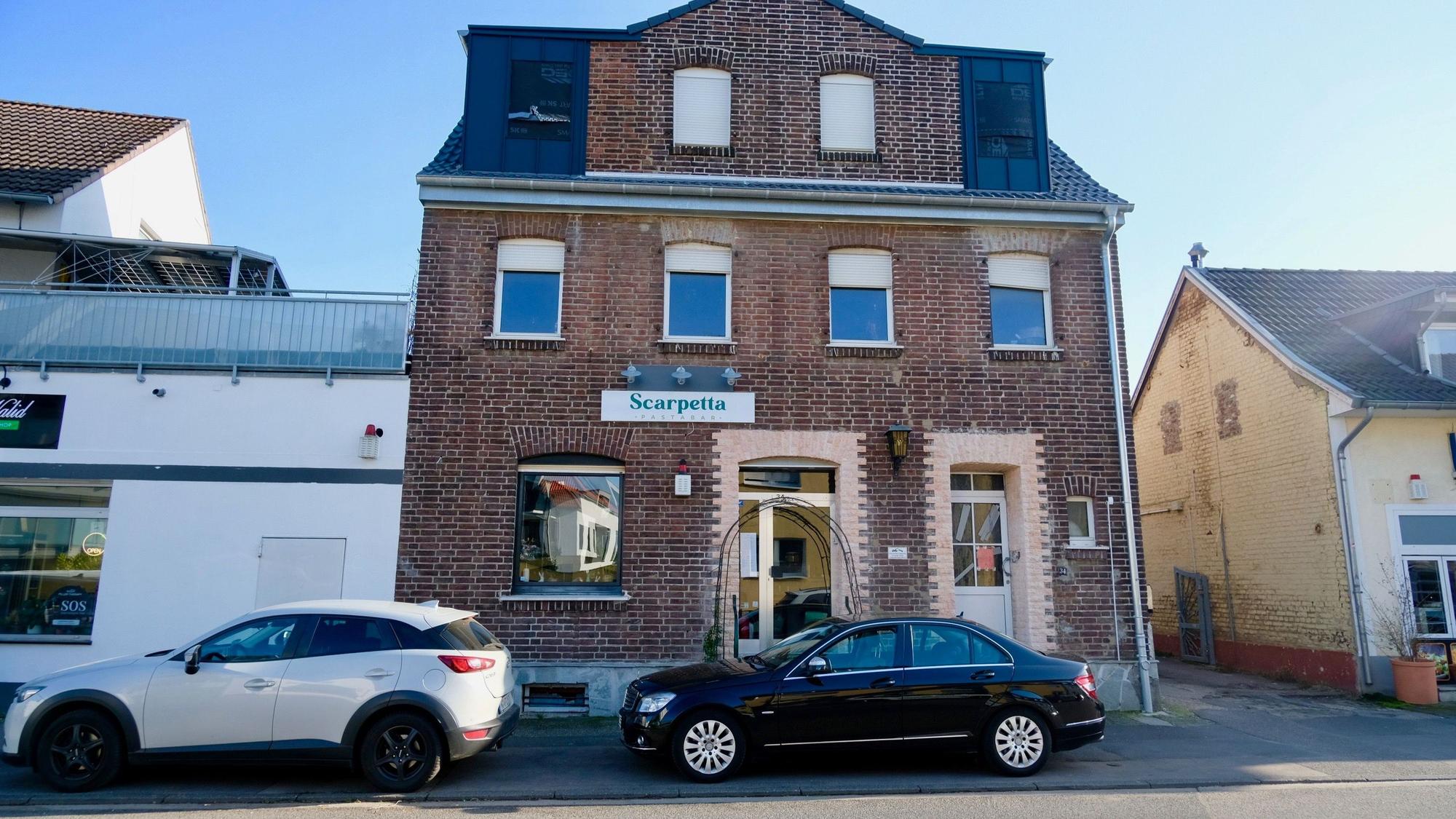 An einem unscheinbaren Klinkerbau hängt das Schild Scarpetta über der gläsernen Eingangstür.