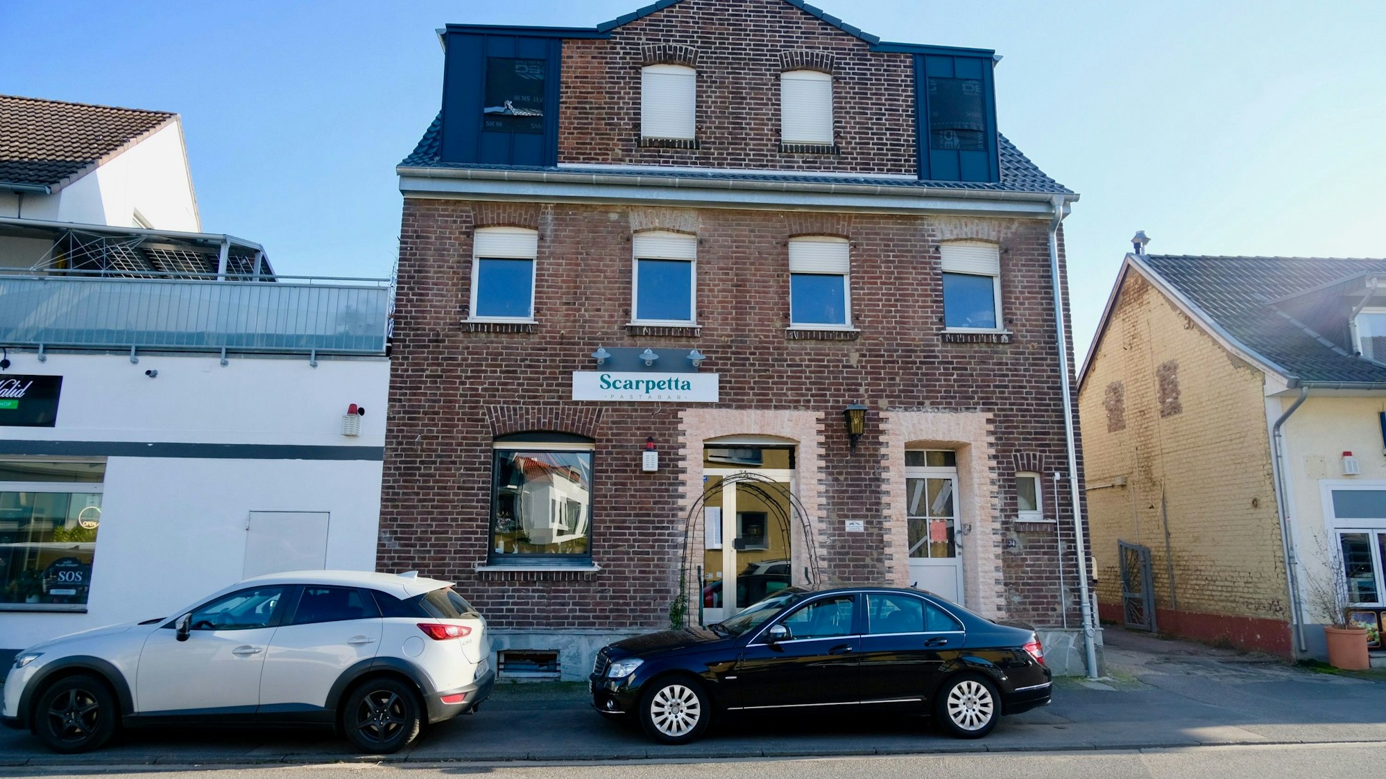 An einem unscheinbaren Klinkerbau hängt das Schild Scarpetta über der gläsernen Eingangstür.