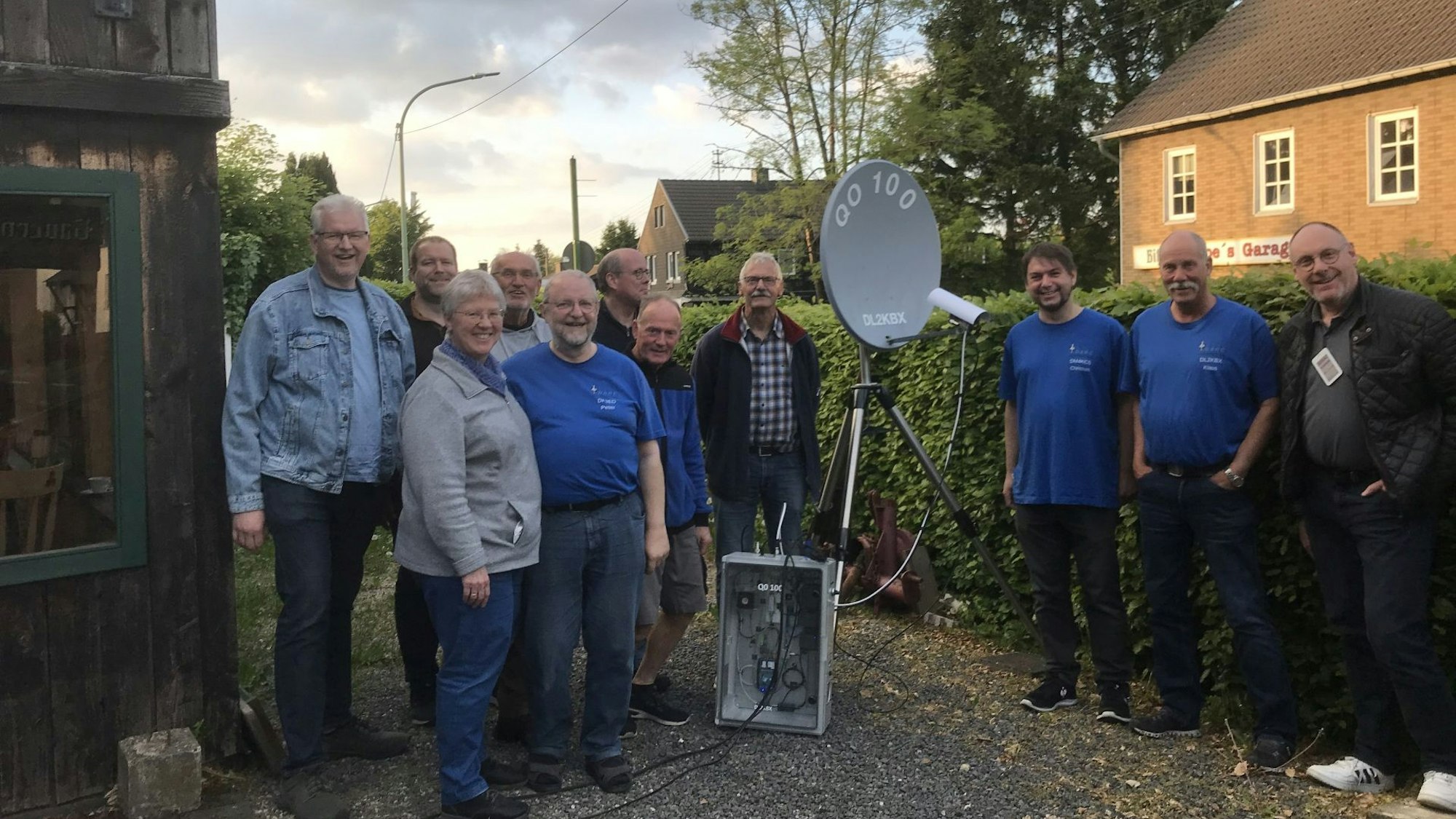 Zehn Männer und eine Frau stehen um eine mobile Satellitenschüssel herum.