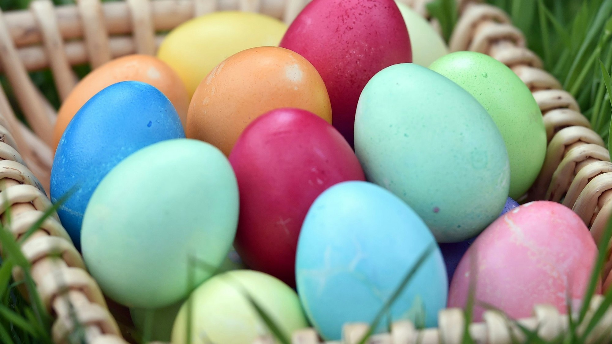 Selbstgefärbte Ostereier liegen in einem Körbchen auf einer Wiese. (Symbolbild)