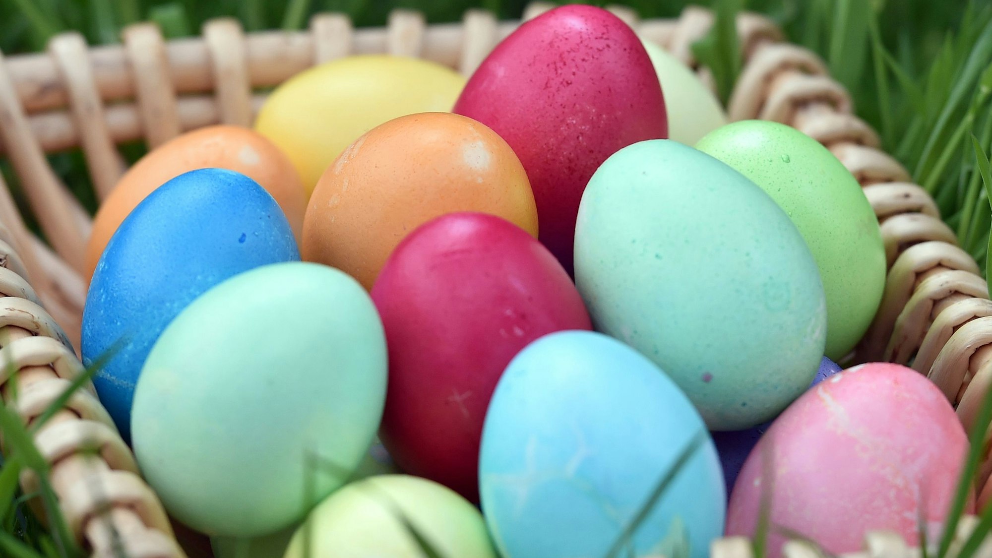 Selbstgefärbte Ostereier liegen in einem Körbchen auf einer Wiese. (Symbolbild)