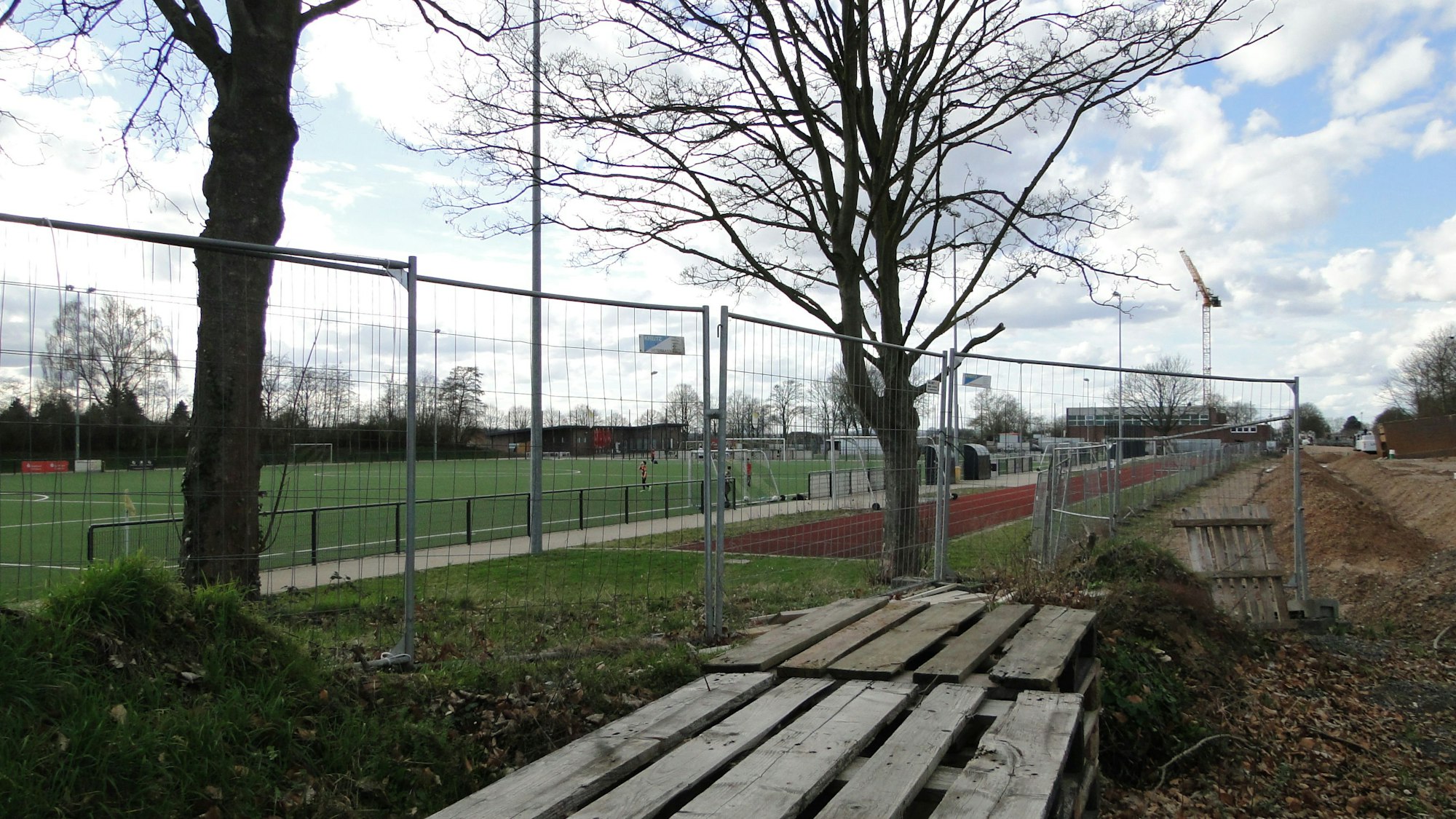 Am Rande eines Sportplatzes steht ein Bauzaun.