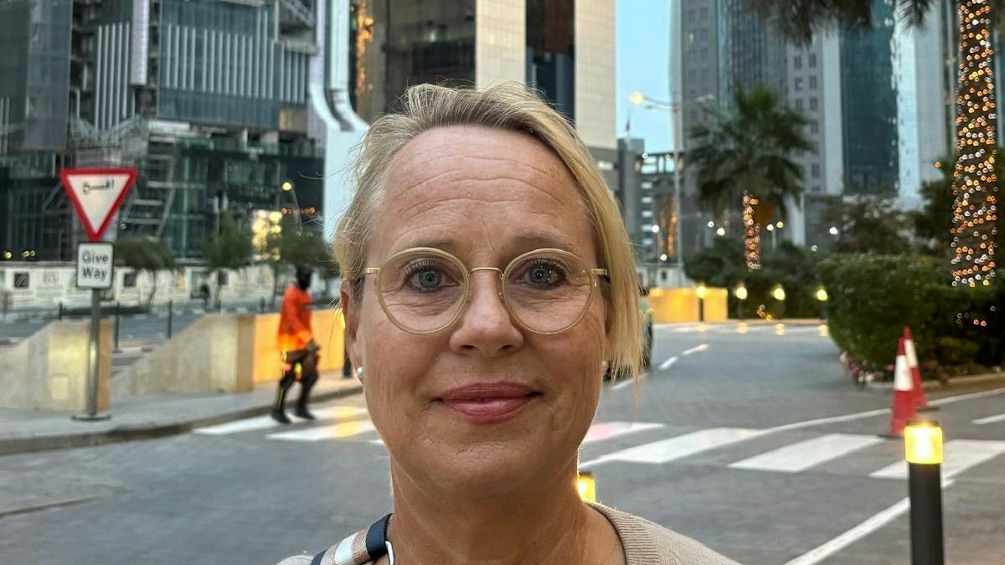 Eine Frau, im Hintergrund Straßen, Hochhäuser und Palmen.