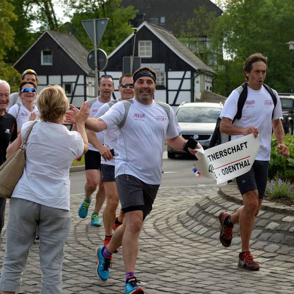 Marathonläufer werden in einem Kreisverkehr von Passanten freudig begrüßt.