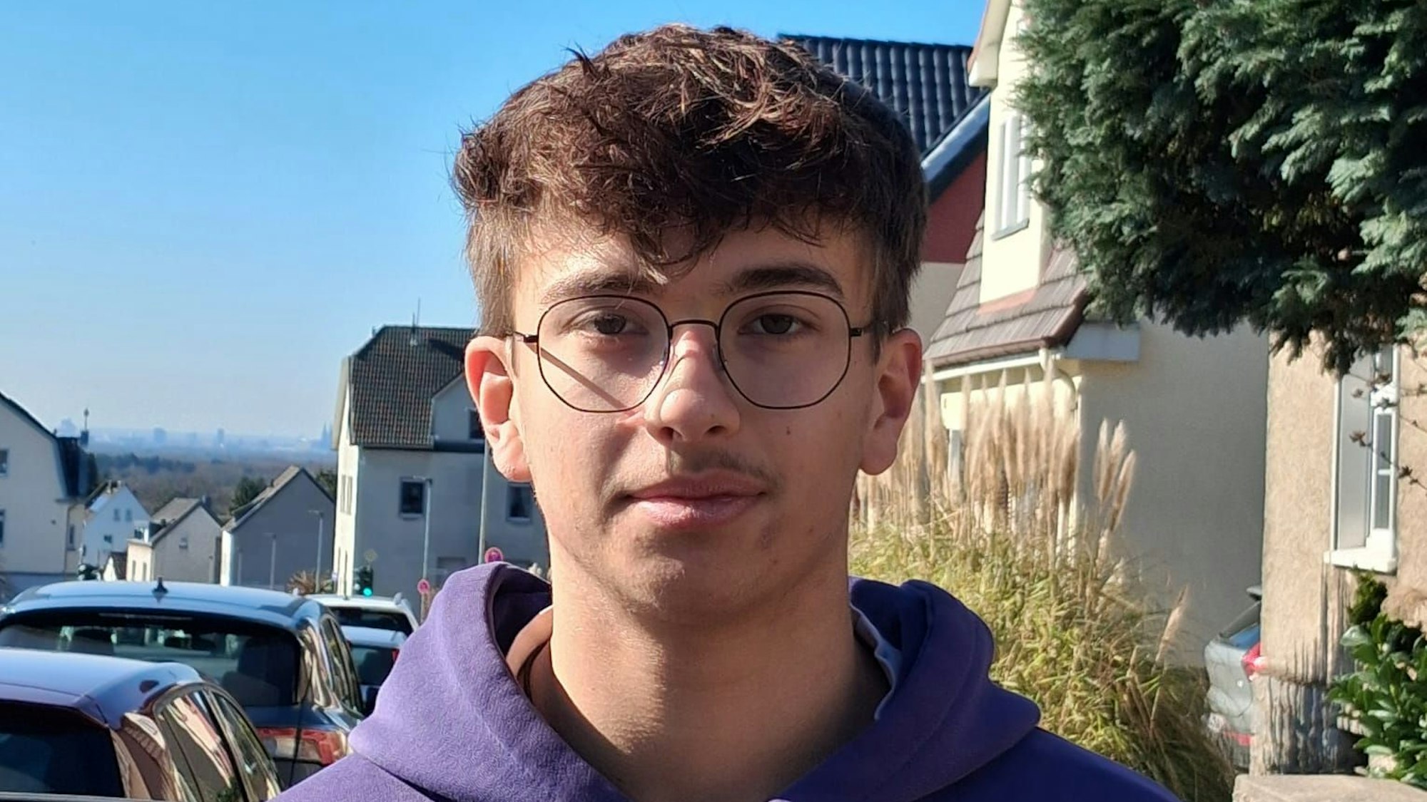 Ein junger Mann lächelt leicht in die Kamera.