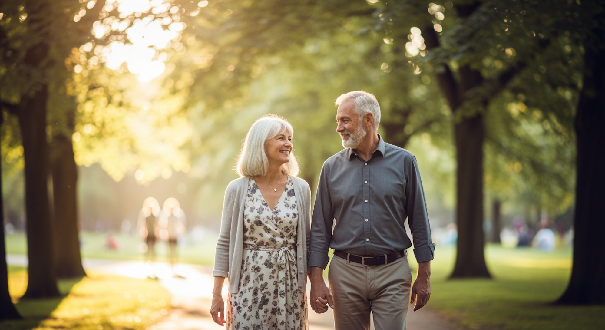 Ein älteres Paar, das Hand in Hand durch einen sonnigen Park spaziert