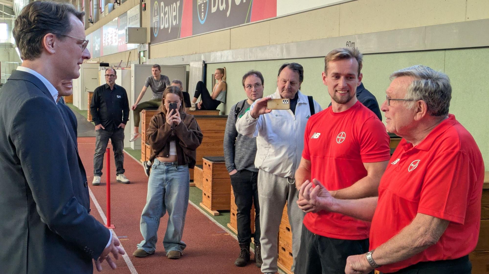 Hendrik Wüst unterhält sich in der Leichtathletik-Halle mit Johannes Floors und dessen früherem Trainer Karl-Heinz Düe.