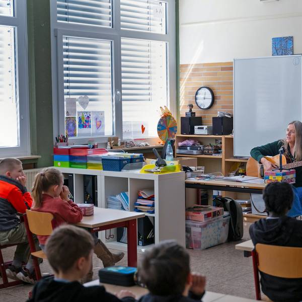 Ein Frau spielt Gitarre im Klassenzimmer.