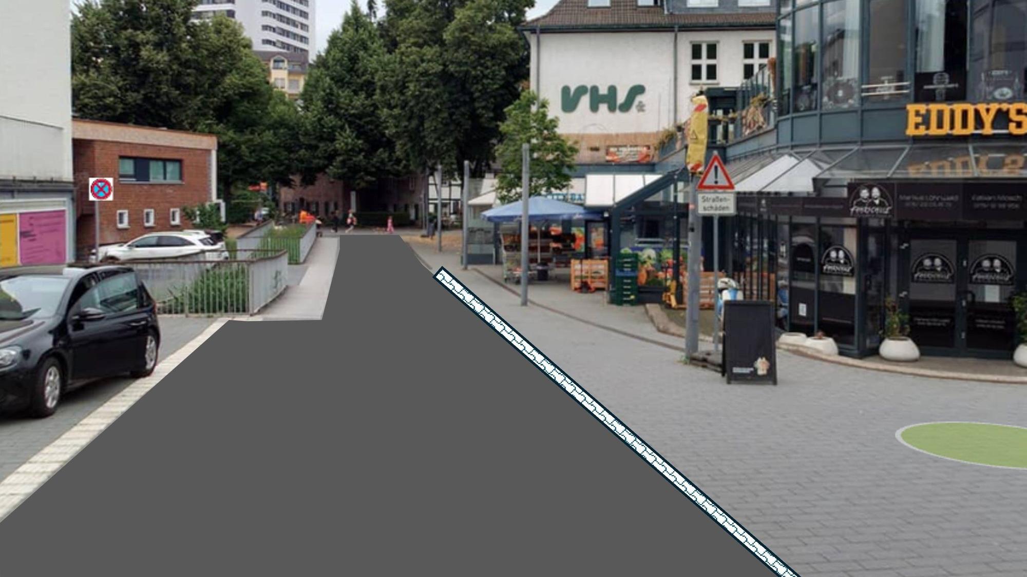 eine Fußgängerzone, auf der linken Seite ist das Pflaster durch Asphalt ersetzt