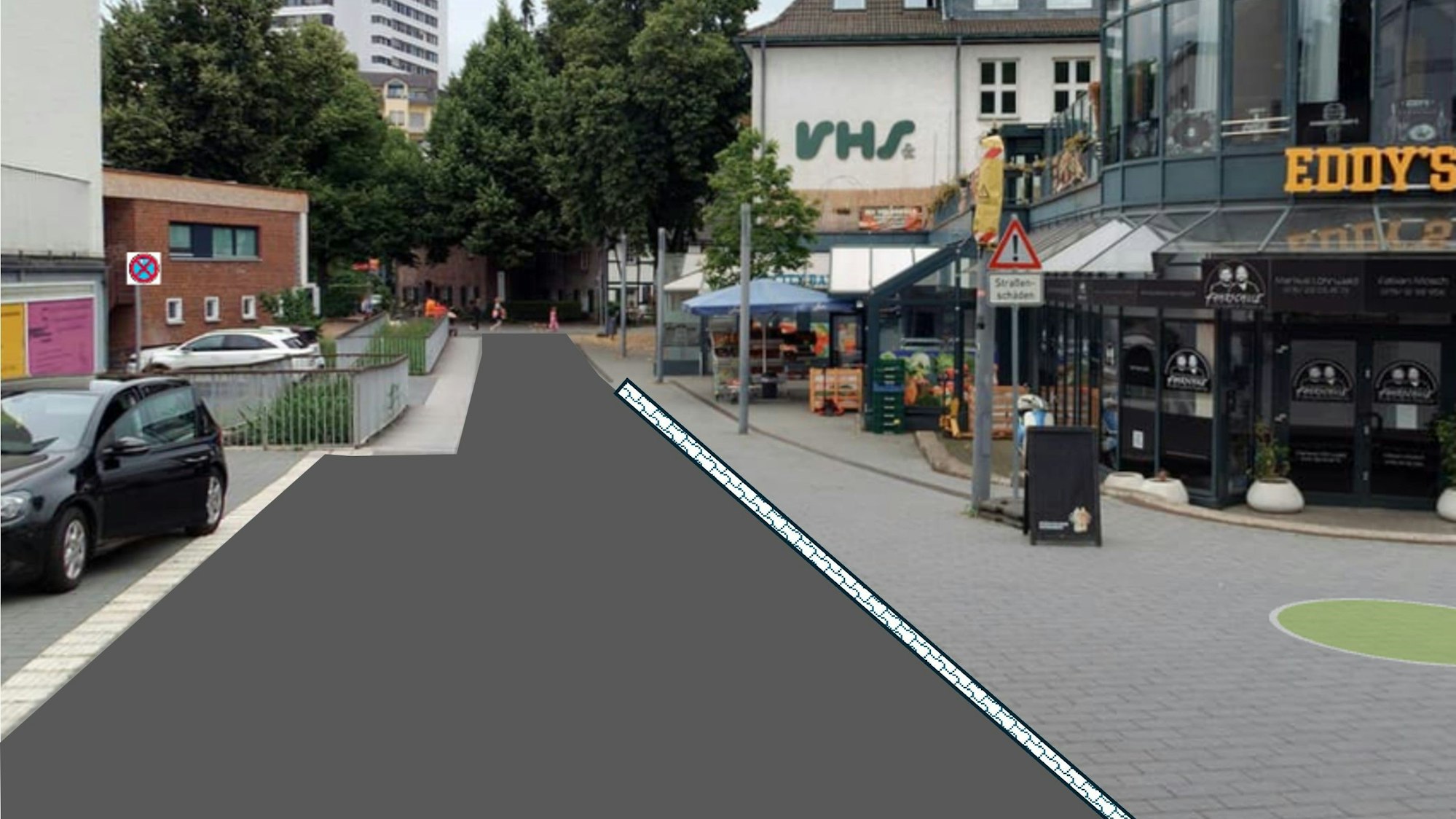 eine Fußgängerzone, auf der linken Seite ist das Pflaster durch Asphalt ersetzt