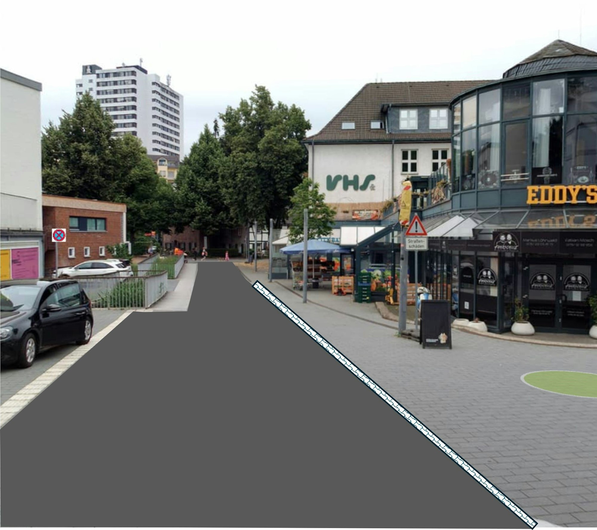 eine Fußgängerzone, auf der linken Seite ist das Pflaster durch Asphalt ersetzt