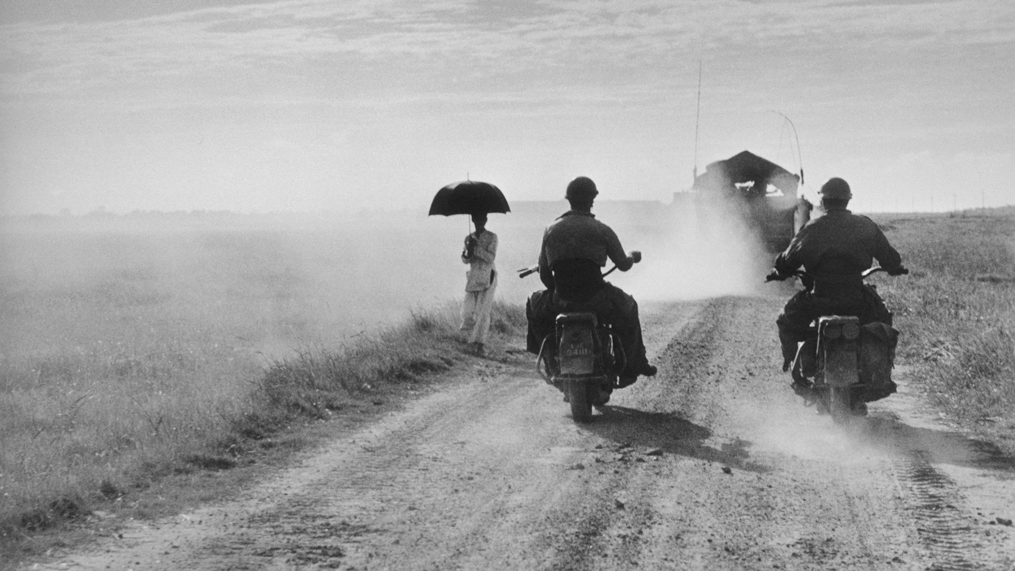 INDOCHINA (VIETNAM). May, 1954. Motorcyclists and woman walking on the road from Nam Dinh to Thai Binh.