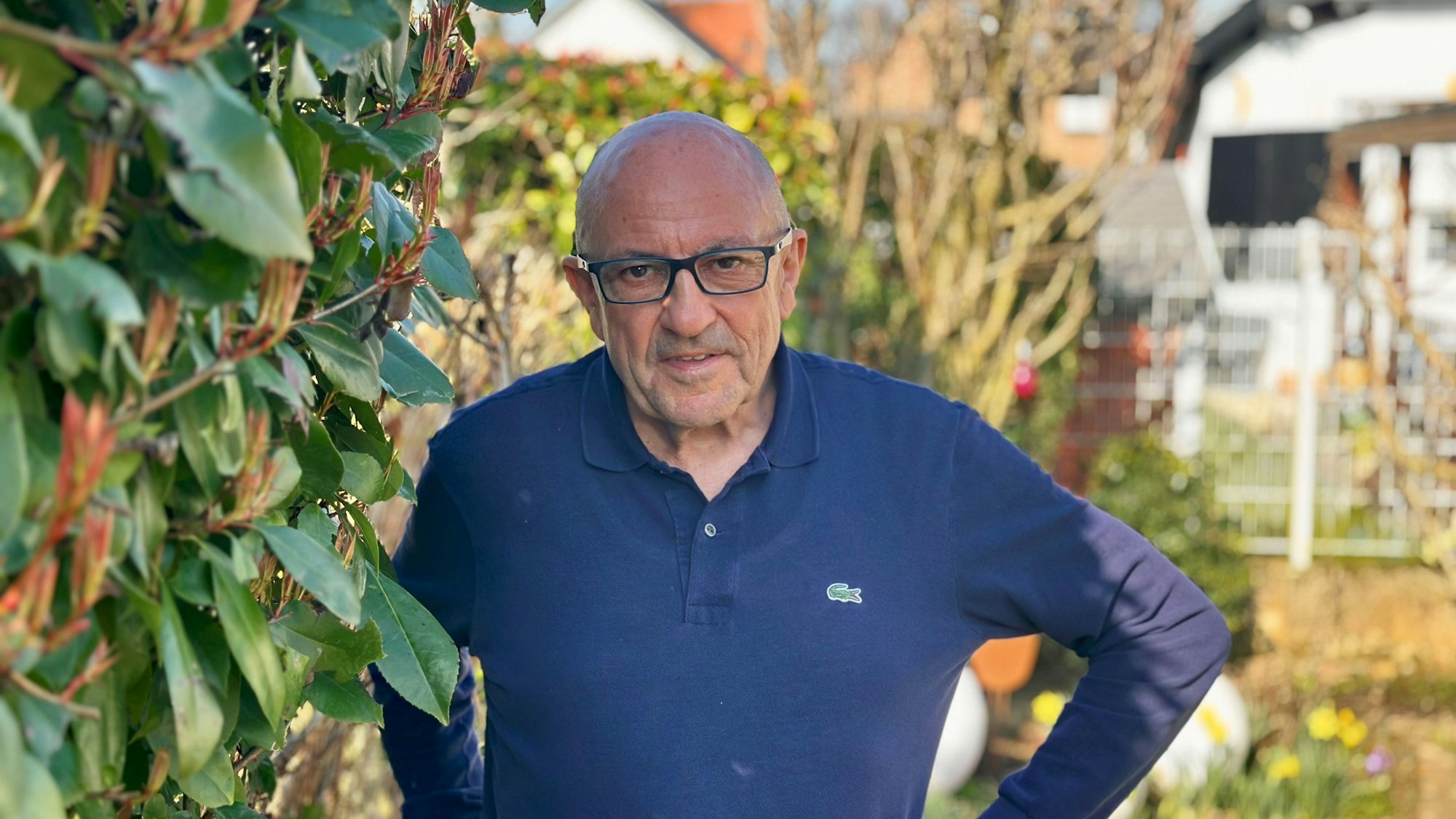 Ein Mann steht neben einer Hecke in einem Garten.