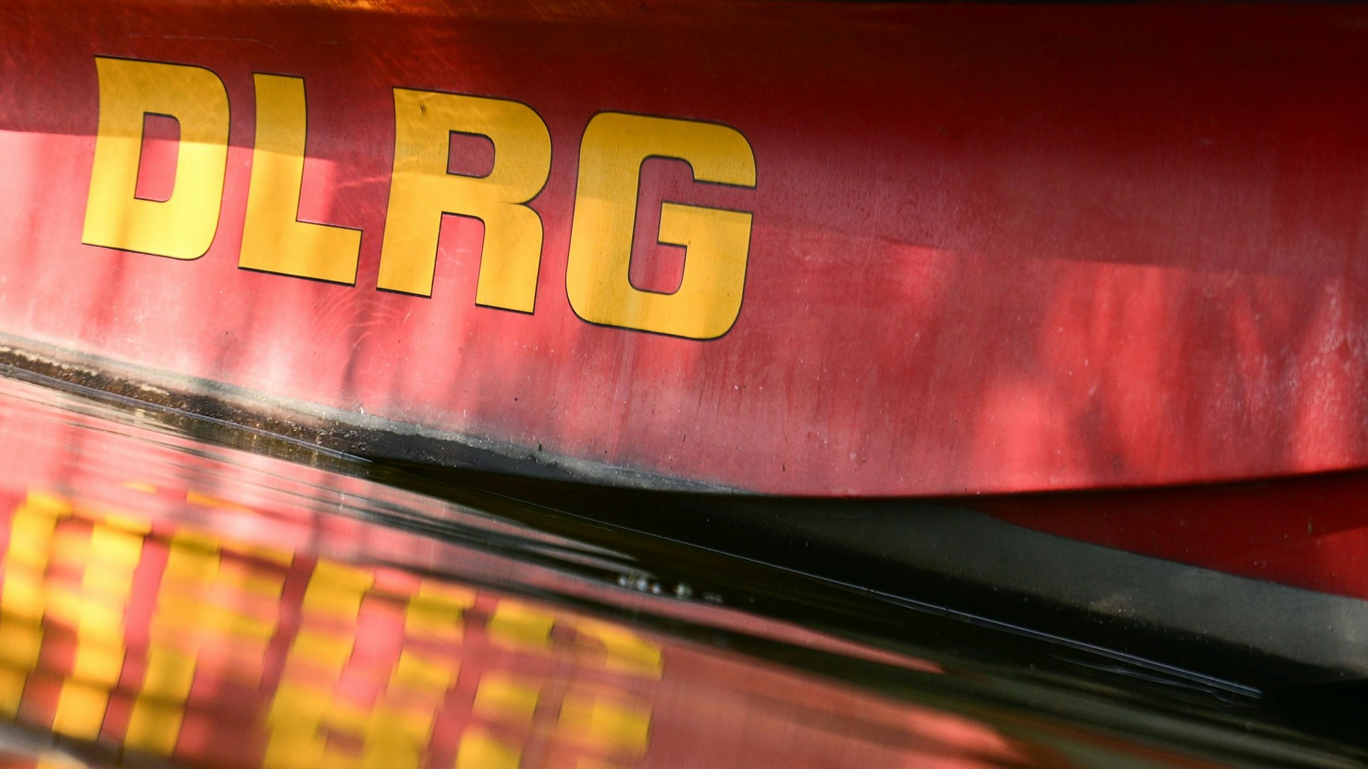 Ein Boot der Deutschen Lebens-Rettungs-Gesellschaft spiegelt sich im Tegeler See an einer Badestelle.