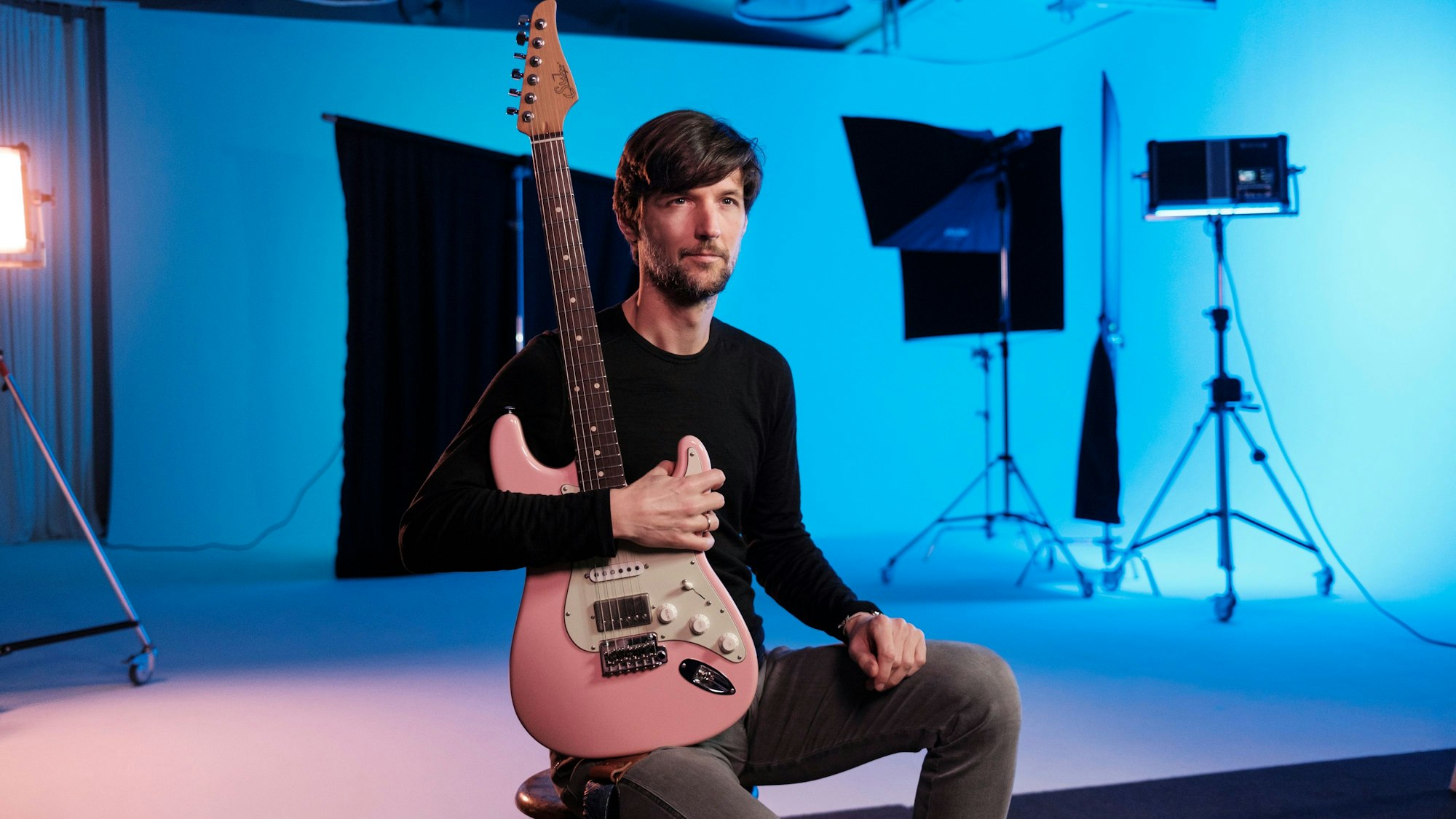 Philipp Brämswig hält seine Gitarre vor der Brust.