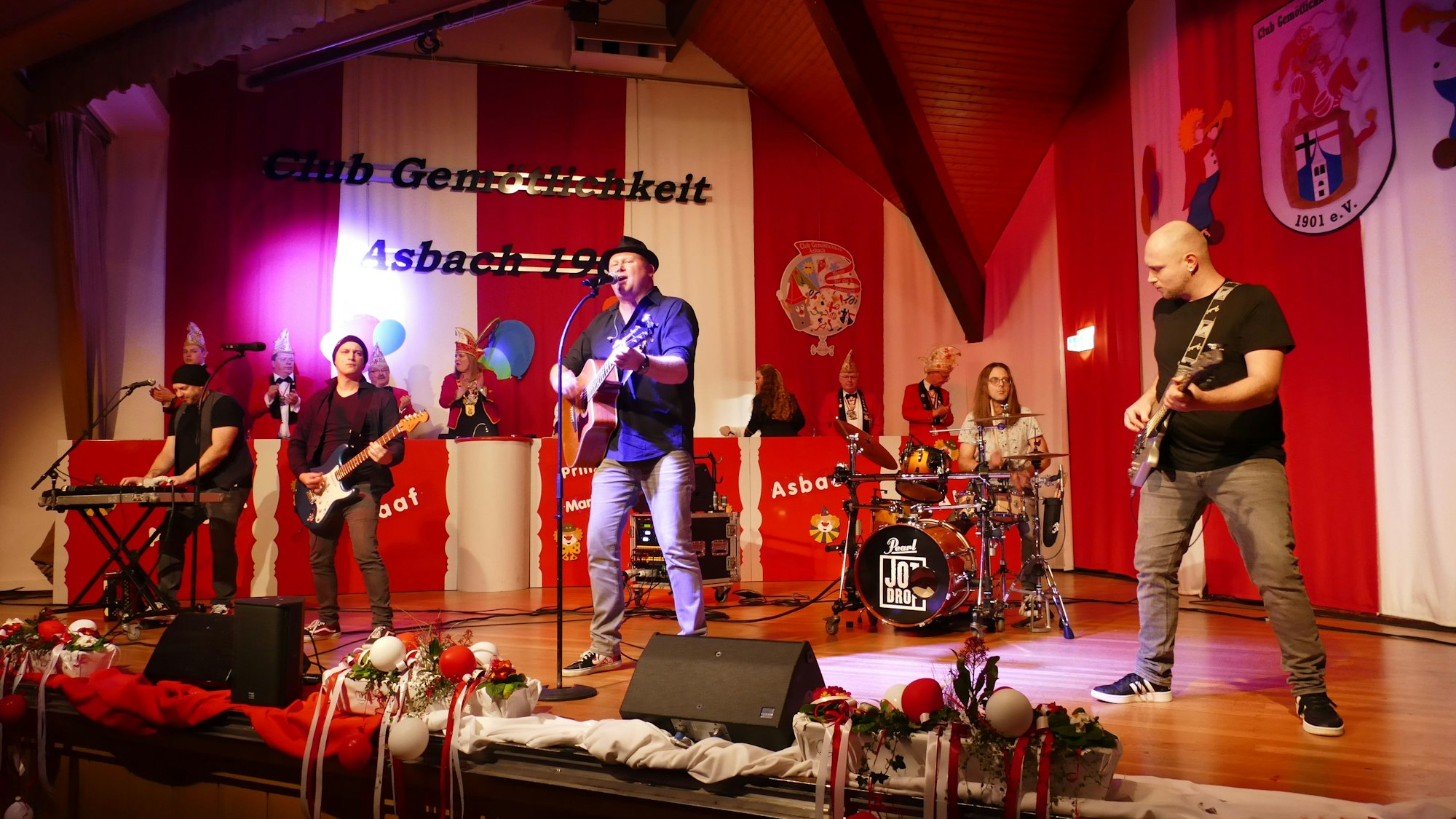 Eine Band auf der Bühne vor rot-weißer Dekoration.