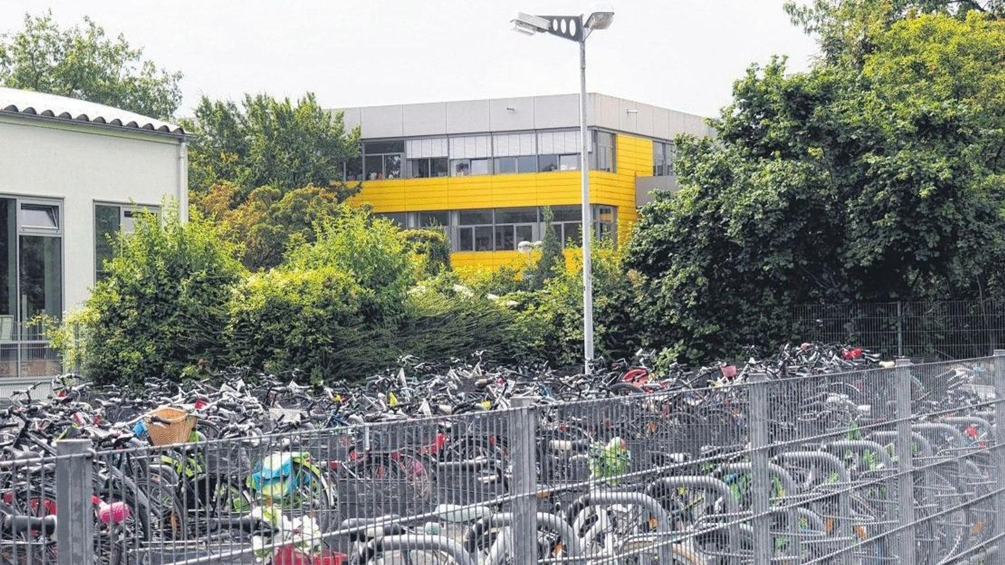 Ein Gebäude mit gelben Fassadenelementen im Hintergrund, im Vordergrund viele Fahrräder.