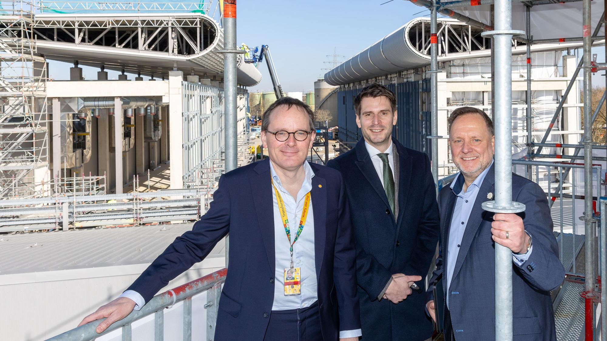 NRW-Staatssekretär Paul Höller (Mitte) besichtigt den unfertigen Bau des Wasserstoff-Elektrolyseurs gemeinsam mit den Shell-Managern Jan-Peter Groot Wassink und Jens Müller-Belau im Energie- und Chemiepark Wesseling.