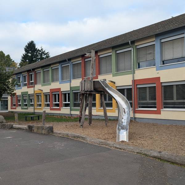 Das Foto zeigt eine Außenaufnahme der Schule und des Schulhofs.
