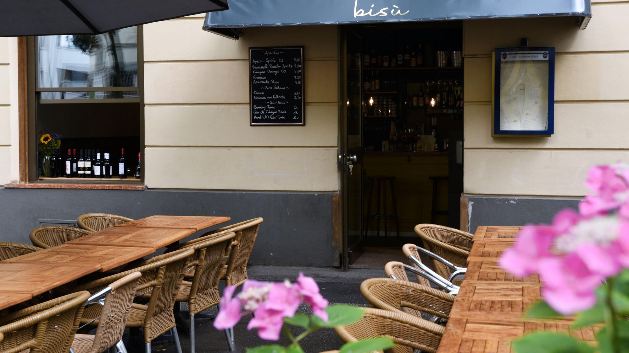 Vor dem Eingang des Restaurants Bisù stehen Tische und Stühle.