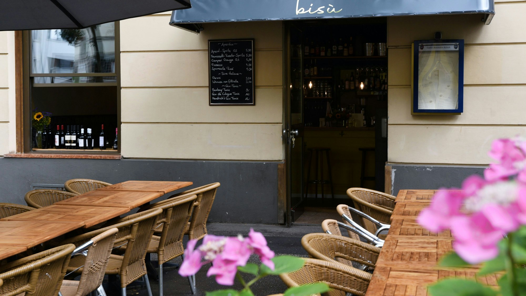 Vor dem Eingang des Restaurants Bisù stehen Tische und Stühle.