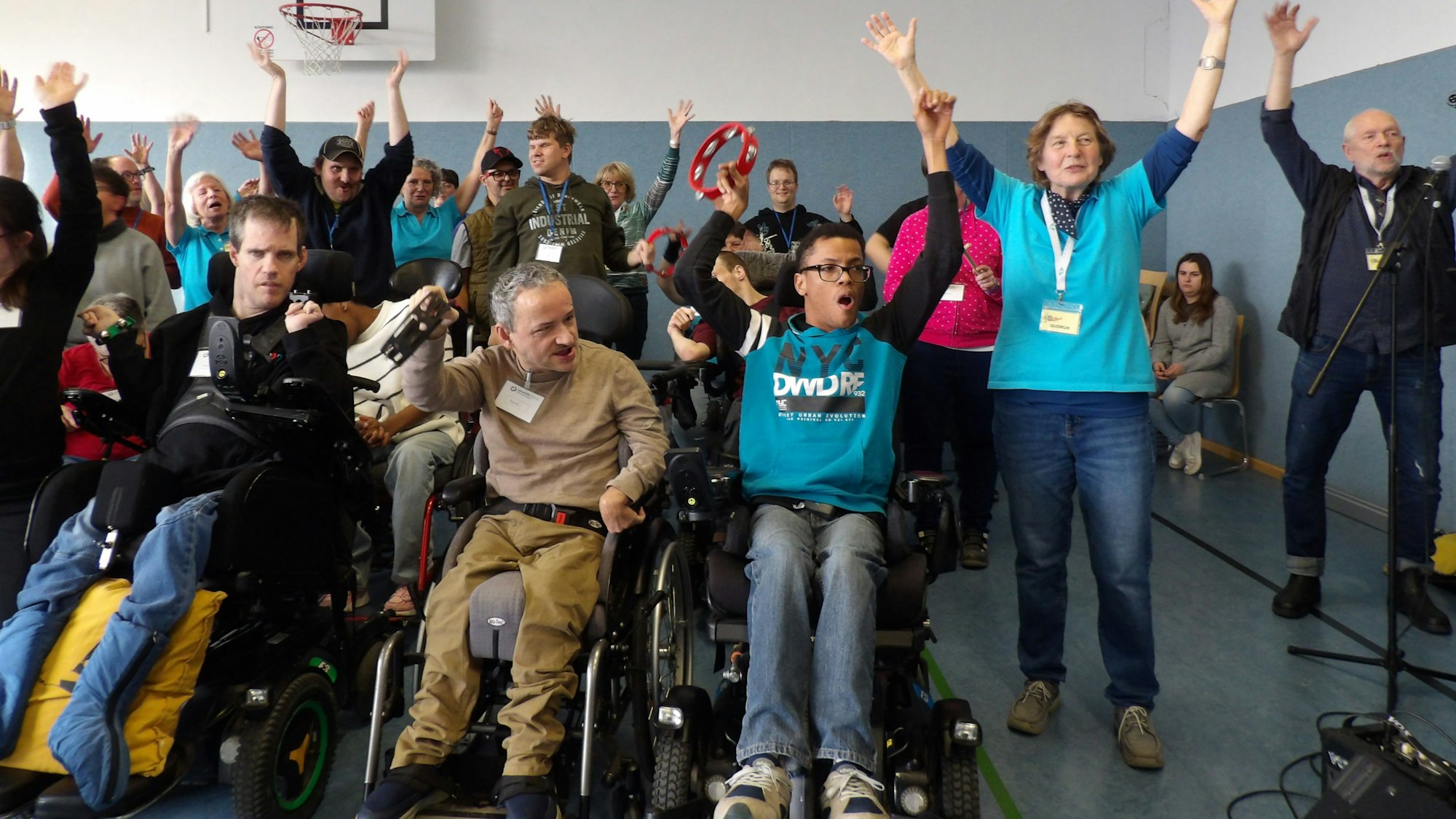 Menschen mit und ohne Behinderung werfen die Arme nach oben.