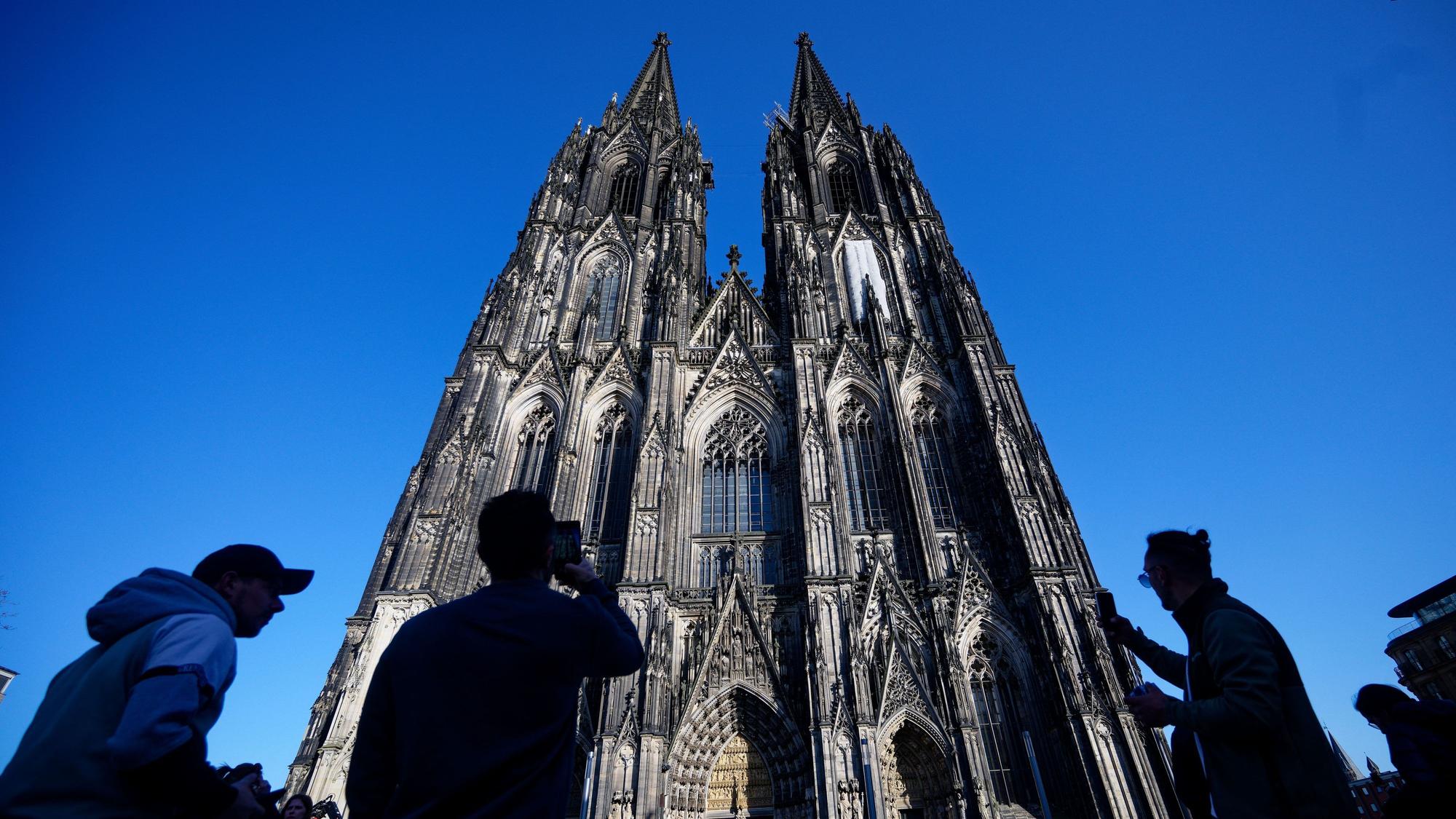 05.03.2026, Nordrhein-Westfalen, Köln: Touristen fotografieren den Kölner Dom. Der Kölner Dom wird Touristen in Zukunft Eintritt kosten. Damit sollen die gestiegenen Kosten für Pflege, Schutz und den laufenden Betrieb des Doms gedeckt werden, wie das Domkapitel auf einer Pressekonferenz mitteilte Foto: Henning Kaiser/dpa +++ dpa-Bildfunk +++