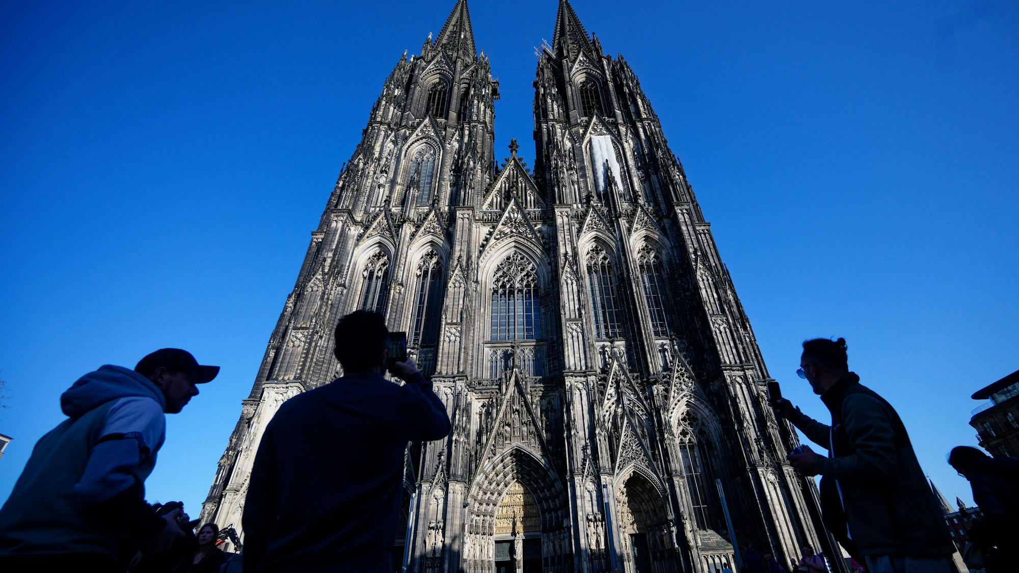 Touristen fotografieren den Kölner Dom. (Symbolbild) Wenn sie hineinwollen, müssen sie ab Juli eine Gebühr entrichten.